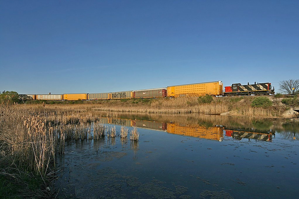 1431 hauls loaded auto racks out of the Ford plant, past the pond down into Oakville Yard.
