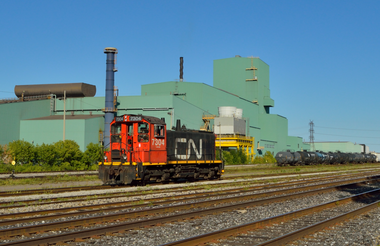 In the heart of Steeltown!  History rides the rails at the CN Steel Center in industrial Hamilton, where CN SW1200 7304 switches cars around the yard in front of Dofasco Central Shipping.To my knowledge, this was one of two SW1200's on the CN roster, however, only CN 7311 (assigned to the steel transfer facility in Mac Yard) is on the roster.  Can anyone clarify if the 7304 is owned by CN?