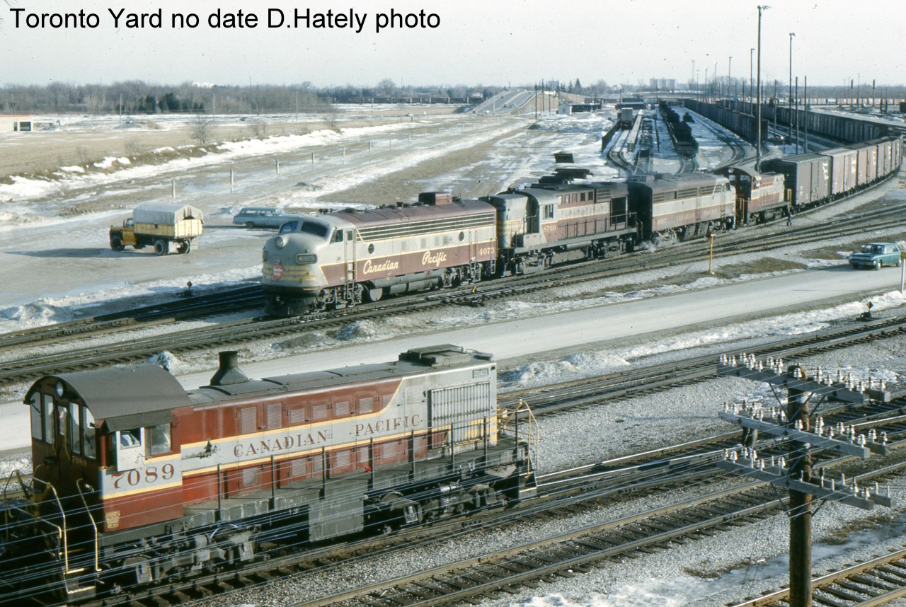 This view from the Finch Ave. bridge shows an eastbound grain train departing Toronto Yard. The power is 4073-8760-4097 and yard engine 6709. The 6709 is an SW-8. The Oshawa yard engine for many years, 6709 is likely returning to Oshawa after some maintenance at Toronto Yard. FP7,4073, a GMD product of October 1952, was regeared to 89 mph and renumbered 1429 in December 1954. As CP moved away from the passenger business the 1429 was renumbered to the original 4073 and back to to 65 mph in October 1965. The extra under frame water tank remains and these FP7s were sometimes used in passenger service in spite of the 65 mph freight gearing.In the foreground MLW S2 7089 goes about switching duties.