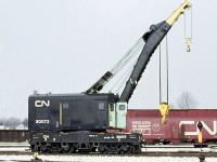 Canadian National "Big Hook" 50073 (a 1920 Industrial Works 120-ton crane) is shown at CN's yard in Fort Erie back on February 9th, 1973. 
<br><br>
Often times before the era of contractor cleanup services, the larger railways had wreck auxiliary trains based out of strategic locations or major divisional points on the system for clearing up derailments. They usually contained a "big hook" suitable for lifting large mainline locomotives that might need rerailing.