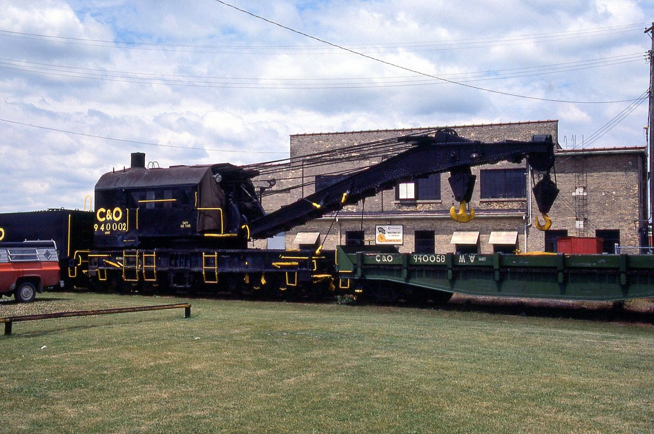 Cheapeake and Ohio 150-ton steam-powered wrecking crane C&O 940002 is pictured with idler flatcar 940058 and tender 940352 by the C&O's roundhouse in St Thomas ON, in June 1985. It was originally built by Industrial Works of Bay City, MI as Pere Marquette DK-5 (DK standing for "derrick") in 1927. It became C&O 940002, and later served under CSX (not relettered from C&O) until being retired and scrapped.
