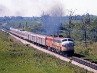 After passing through Woodbridge (no longer a scheduled stop as the station had closed a few years earlier) CP train #12, the Sudbury-Toronto section of The Canadian crosses the Humber River and heads south on the Mactier Sub, passing the white Emery mileboard sign and about to duck under the CN Halton Sub just west of Islington Avenue on the Vaughan-Toronto border.<br><br>CP repainted its 1400/1900-series passenger locomotives and stainless steel Budd equipment used on the Canadian relatively quickly after the new CP Rail branding was introduced in 1968. But, dual-service (freight/passenger) locomotives often found in passenger service, such as FP7 4066 leading, continued to operate in their older colours for years until overhaul or repainting. The trailing repainted FPA2 is likely one of the dual-service 4094-4097 group that also frequented #11/12.<br><br>The consist today is two older lightweight steel baggage cars (one still with the maroon stripe, both painted silver to match the newer Budd stainless steel cars), a baggage-dormitory car, coach, Skyline dome, a Manor and a Chateau sleeper, dining car, and the dome-observation "Park" car on the tail end.<br><br><i>A wider approach shot of the same train</i>: <a href=http://www.railpictures.ca/?attachment_id=25781><b>http://www.railpictures.ca/?attachment_id=25781</b></a>