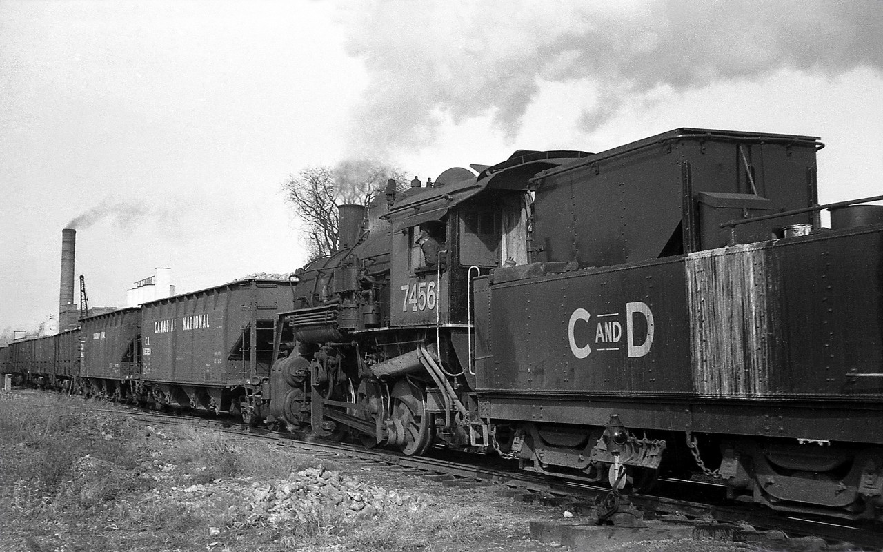 Canada & Dominion Sugar 7456 (a former Canadian National 0-6-0, nee-GTR, that was first leased by C&D and later purchased) switches hoppers and drop-bottom gondolas loaded with locally-grown sugar beets into the Chatham Ontario plant in November 1960. Next year the harvest would be switched with a Wabash diesel locomotive, and would be the last year before the plant was torn down.The Canada and Dominion Sugar Company was a result of the 1930 merger between sugar producers Canadian Sugar Refining Company (of Montreal) and The Dominion Sugar Company of Chatham ON. By this time, the company had just changed names in 1959 to Redpath Sugars Ltd.The Chatham plant was built by the Dominion Sugar Company in 1915 and located north of Merritt Ave and King St. West just south of the Thames River, served by rail from a spur off CP's Windsor Sub. The opening of the new Redpath Toronto plant on the harbourfront of Lake Ontario (with access to the new St. Lawrence Seaway) in 1959 resulted in the closure of the Chatham plant in short order. The end of the use of sugar beets in Ontario plants would follow a few years later when the Wallaceburg plant was closed in 1968 (the Toronto plant used cane sugar).7456 was saved from the scrapper in 1964 by the Ontario Government for inclusion in a proposed rail museum with other steamers (that never came about), and today is presently on display at the Heritage Village in Sidney, Michigan.