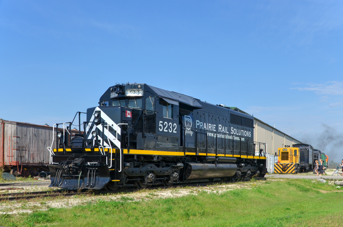 A freshly repainted SD40. VLSX 5232 may be the only 'straight' ex-CN SD40 still in service. It was repainted out of its faded zebra stripes during the past couple of months and sports a paint scheme very similar to that worn by SD40's on the New Brunswick East Coast not too long ago. Here it sits in the morning sun in the small Prairie Dog Central yard at Inkster Junction. Steam from 4-4-0 PDC 3 is visible in the background, it will leave with an excursion train in not too long, with passengers arriving to board the train.