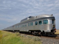 <b>Tail end of a 100-axle passenger train.</b> Park car <i>Glacier Park</i> brings up the rear of VIA's <i>Canadian</i> as it heads west towards threatening skies with 2 F40's and 23 cars.