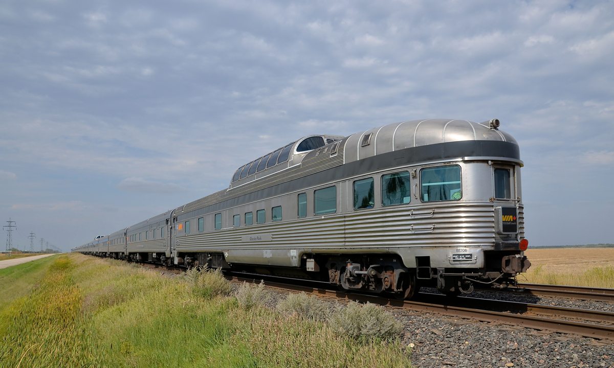 Tail end of a 100-axle passenger train. Park car Glacier Park brings up the rear of VIA's Canadian as it heads west towards threatening skies with 2 F40's and 23 cars.