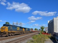 <b>The 'overpass to nowhere' will soon go somewhere.</b> CN 327 has a pair of CSX ES40DC's and a CN GP38-2W (CSXT 5273, CSXT 5277 & CN 4762) and 97 cars as it passes an overpass with an interesting story. Transports Québec started building an overpass which would bring highway 20 to the nearby airport about 6-7 years ago, but then realized that it had not obtained permission from CN or CP to build pillars on their right of way. Part of the overpass at right had sat unused and useless all this time, but work has finally begun anew as an agreement with the railways was reached a year ago.