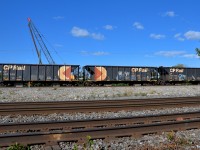 CP 119 has four multimarked hoppers (the first is out of sight at left) right behind the head end as it departs Dorval.