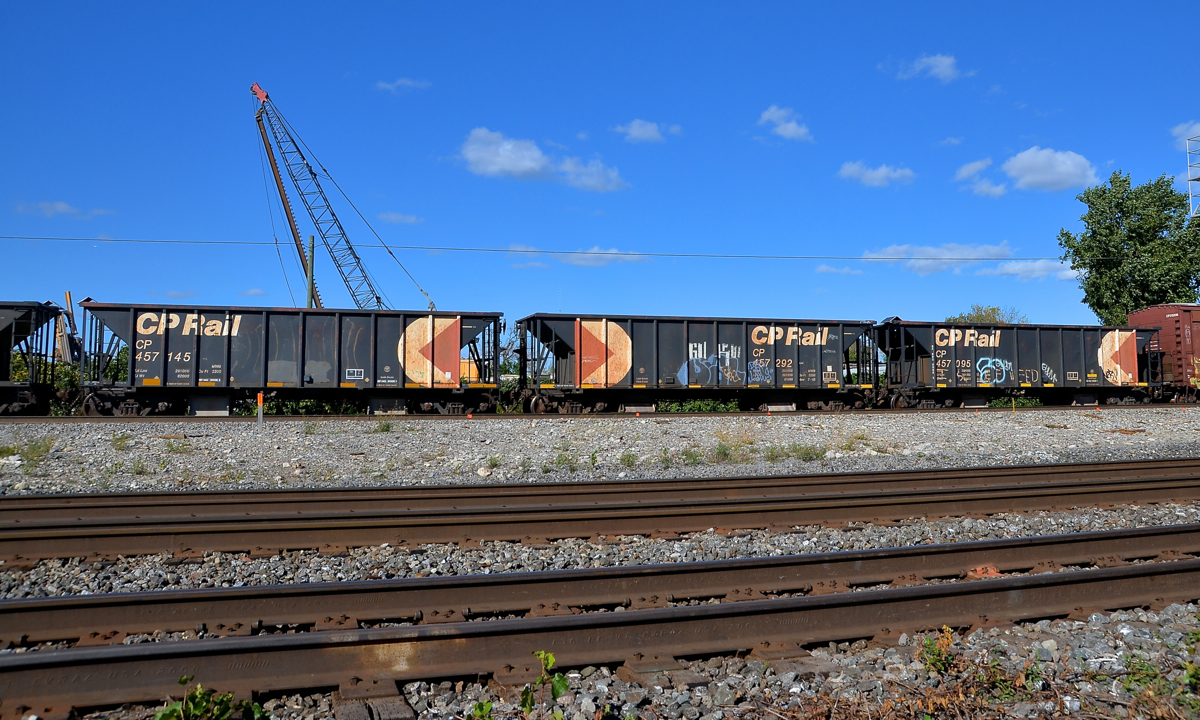CP 119 has four multimarked hoppers (the first is out of sight at left) right behind the head end as it departs Dorval.
