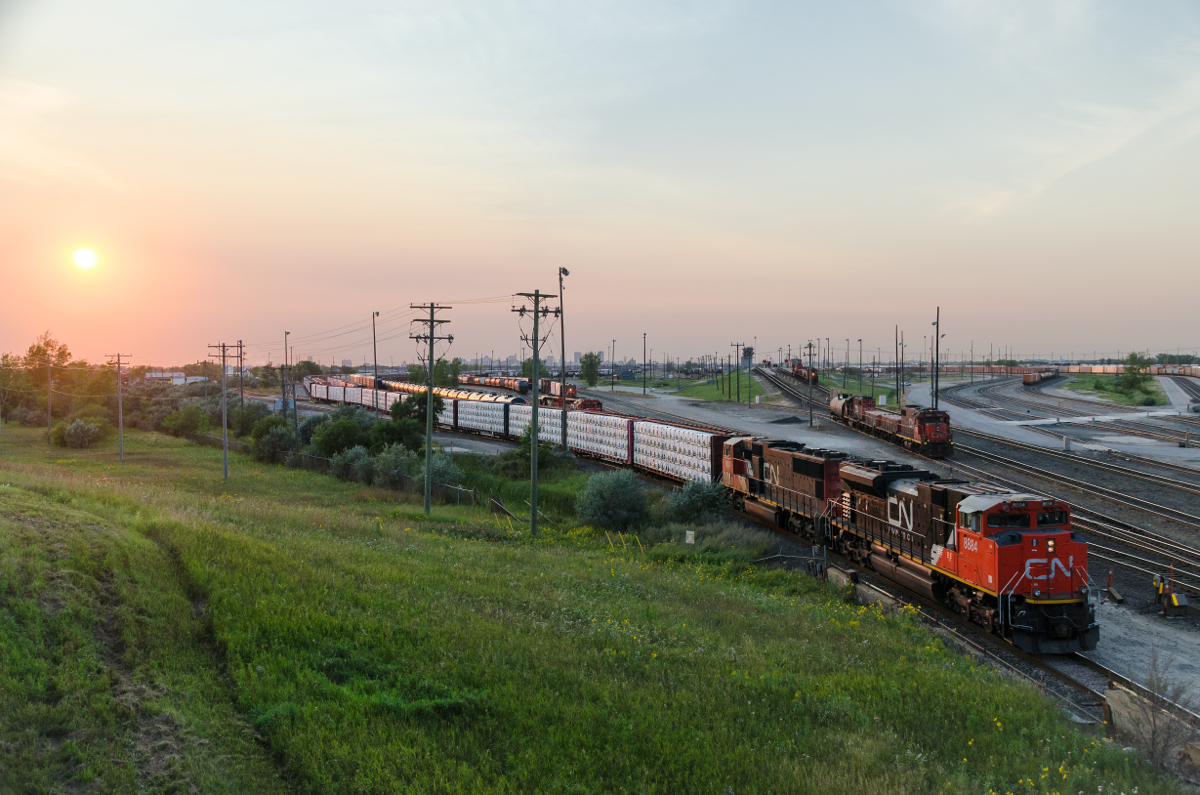 CN 8884 & CN 5613 lead an eastbound out of Symington Yard close to sunset. At right is the hump, with two hump sets working.