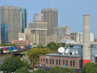 <b>Through downtown Winnipeg.</b> CN 2915 leads CN 101 through downtown Winnipeg. CN 2939 is mid-train and new ET44AC CN 3079 is on the tail end of this long (14,147 feet) intermodal train.