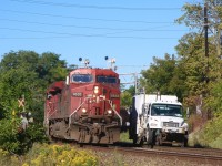 A CP high rail truck occupies the north track at Streetsville. The workers are busy maintaining the switch into the Ardent Mills facility and are briefly taken away from their work in order to inspect an eastbound train as it thunders past. 