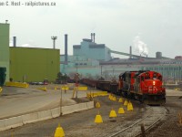 Here's another shot for Dave Young - this isn't the Steel Train, nor is it CN - it's a SOR local lifting raw steel billets in Gondolas using whatever CN power was assigned to 'em. (The steel train 599/598 ran late late afternoon west / early morning loaded east often in darkness, so I suspect CN power could be used for a mid-day job without issue). Stelco deserved about a switch a day from each railway (SOR and CP) in this time-frame after the Chinese economy went all hot and steel was in HOT demand. US Steel emerged to buy Stelco not long after this photo was taken and continued to pump out steel until the blast furnaces were idled in 2010. The bloom was off the rose - Chinese steel companies were (and continue to) dumping cheap steel on the market and steel prices have been in the tanks ever since (there has been some recovery in 2016 though). BlackRock Investments (A New York  Hedge fund) has emerged as the winner to take over the former Stelco - away from US Steel and while I shudder at the thought of another hedge fund meddling (Since it'll just be another kick at the union and their Pensioners) if the economy does recover it's highly possible Stelco may once again rise from the ashes.<br><br>Photo notes: Nikon D70, 50mm f/1.8 on a dreary winter day with no snow, typical of the time.
