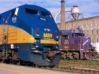 VIA train #84 has just backed out of Kitchener yard and has positioned itself along side GEXR GP38AC #3843, better know by railfans as "Barney", after loading the train will head to Toronto. In the future train #84 schedule would be extended to starting its day in London, before the start up of GO Transit rail service out of Kitchener would abolish the train completely. As for Barney it's stay on the Goderich-Exeter would end a few years later when it was transferred to sister RailAmerica shortline New England Central. Today it wears a coat of Genesse Wyoming orange. The landmark Krug furniture factory in the background is still in operation today much as it has been for close to a century.