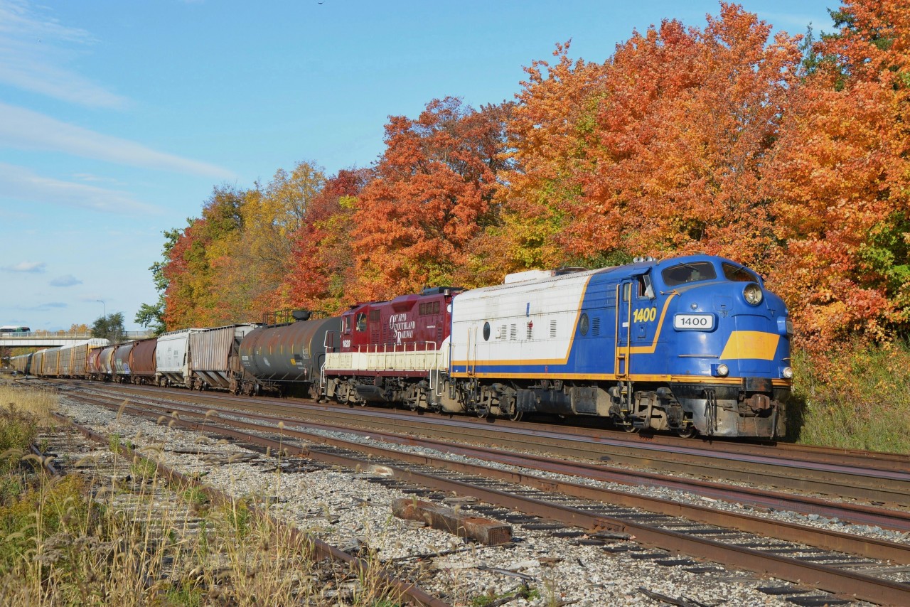 Colourful consist, sunshine / clear skies and scenic foliage ... this railfan's delight!  OSR 1400 FP9u and OSR 1620 GP9 chug back through Woodstock Yard heading west for home rails (after performing a series of shunting moves) with some mixed freight and a large lift of autoracks retrieved from Coakley for return to Ingersoll.