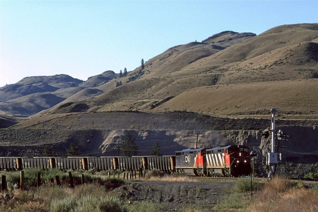 The first train after sun-up is a westbound coal led by a couple Cowled GE's. 
CP's line is clearly visible above this train.