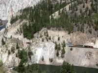 This is not the typical view of White Canyon, however, part of that view can be seen at the far left. That rocky part appears to have been severely degraded by super-heated fluids leaching out some soluble minerals. This left behind a much weakened formation. CP wisely chose the opposite river bank to build their railroad. 
The train is an eastbound manifest being led by a couple GE's.
