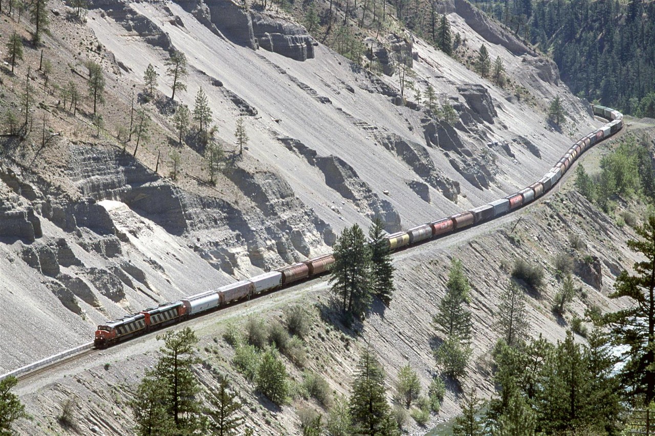A westbound grain train is in the eastern end of White Canyon, where loosely consolidated sediments form the walls (likely the result of glacial damming in the downstream Lytton area and subsequent flooding of this valley. This, of course, and the fact that the white rock in the area is easily weathered).