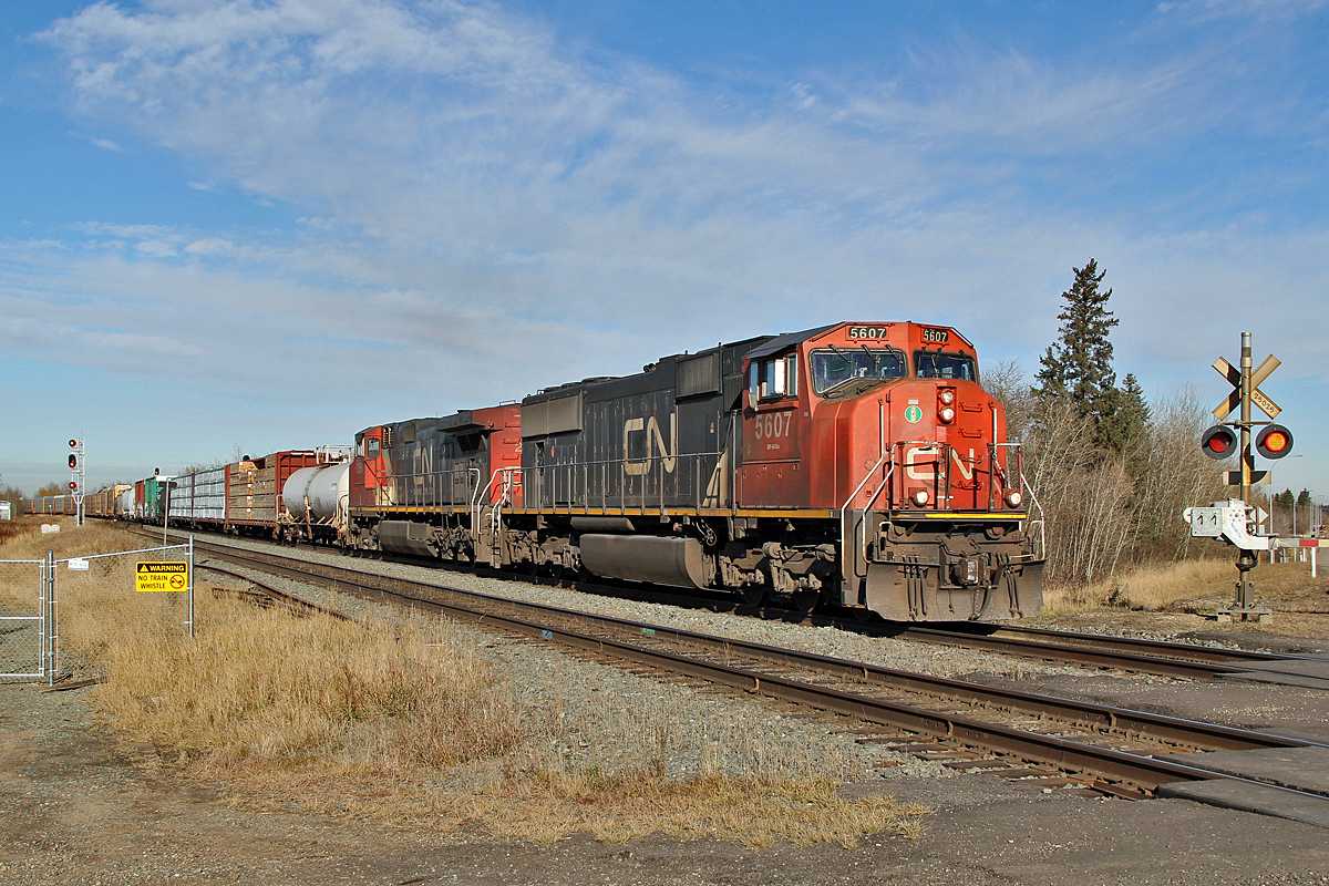 With an assorted load in tow SD75I CN 5607 and Dash 9-44CW CN 2651 power up the hill through Ardrossan.  The range road 222 crossing is now a "no train whistle" crossing, the new safety fence is seen on the left.  How exactly does this fence improve safety?