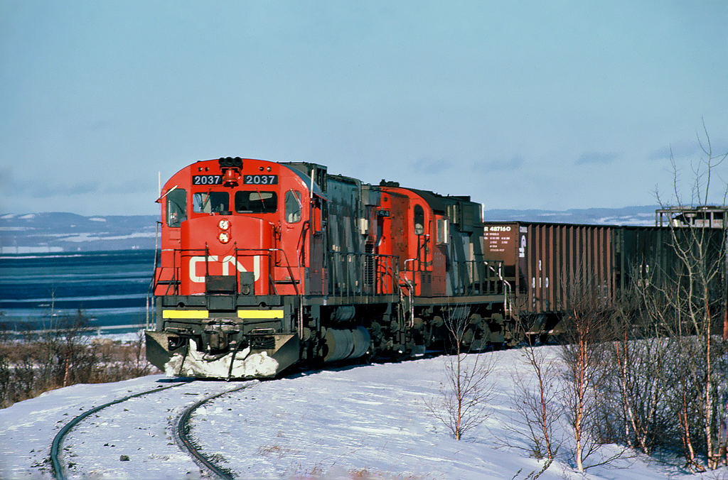 Canadian National MLW C-630M No.2037 with MLW RS-18 No.3654 on the Belledune spur along the shore of Chaleur Bay, in northeastern New Brunswick December 21, 1986.