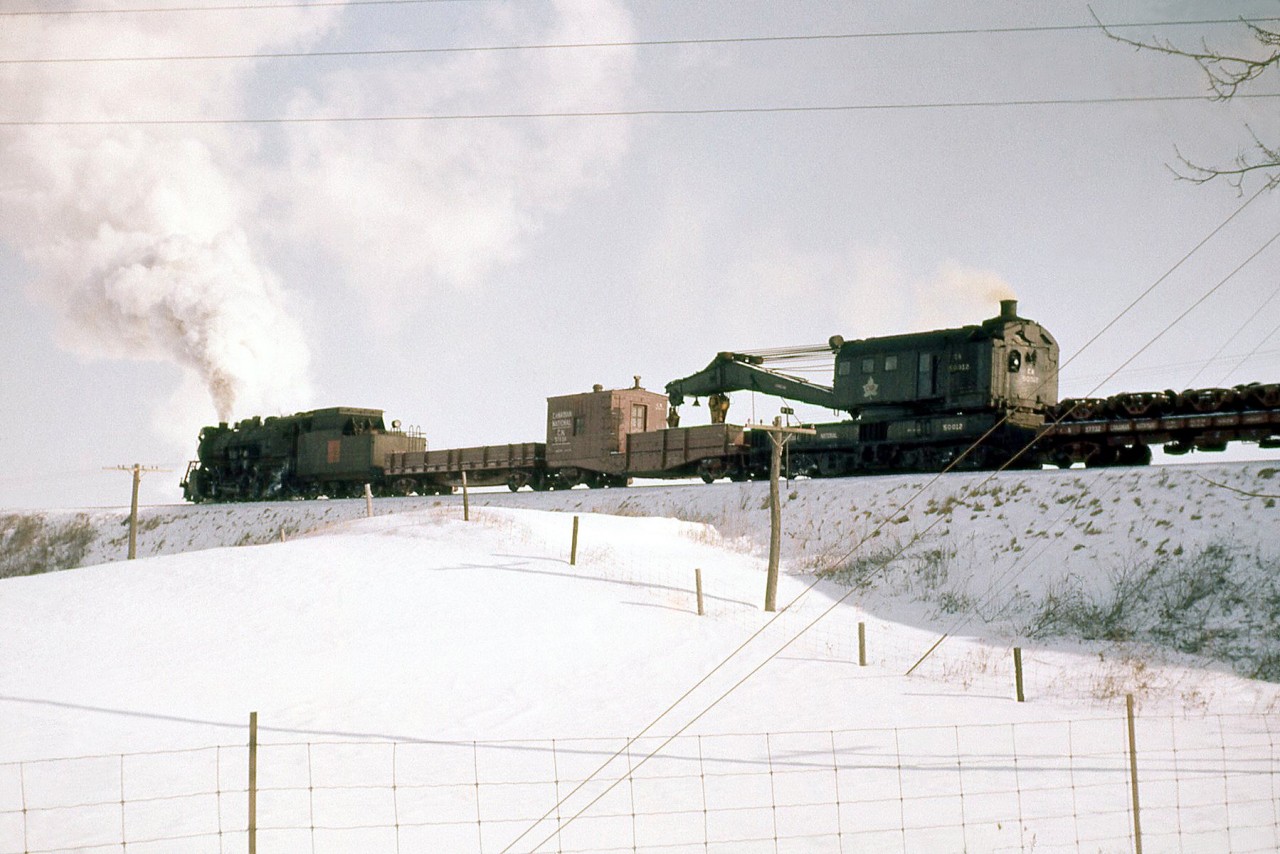 A Canadian National auxiliary train heads north on the Fergus Sub south of Branchton (just north of Highway 5). In consist trailing the steam engine is CN "Hook" 50012, a 200-ton steam powered wrecking crane built by Industrial Brownhoist in 1928. Where this train came from I could not find out - possibly Hamilton (did they base an auxiliary there?) Toronto or London? This is my only photo of a steam powered auxiliary. While they saw infrequent use, most of the large old steam wrecking cranes on CN & CP ended up being converted to diesel power in the years following the end of steam (and some built new as diesel cranes).