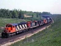 CN SD40 5035 leads GP9's 4514 (outfitted for snowplow service in southern Ontario), 4520 and 4576 on an eastbound up the Halton Sub near "Mile 30", north of Milton on June 1st 1979. The flatcar just behind the power is carrying a narrow-gauge export boxcar, possibly built by National Steel Car for Africa.