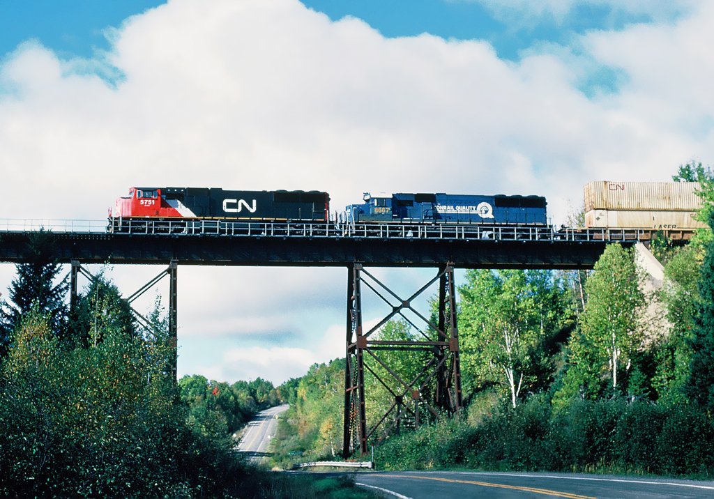 CN EMD SD75I 5751 and CSX SD50 8667 former Conrail 6757, on the Montreal-Halifax mainline with eastbound 148 intermodal train crossing a high trestle at milepost 60.6 on the Pelletier Sub., September 29, 2001.