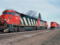  One year old Canadian National GE C40-8M's number 2414 and 2420 are waiting for a meet with southbound CN 402 with in the lead GP40-2L(W) 9586 at Rogersville, New Brunswick April 20, 1991