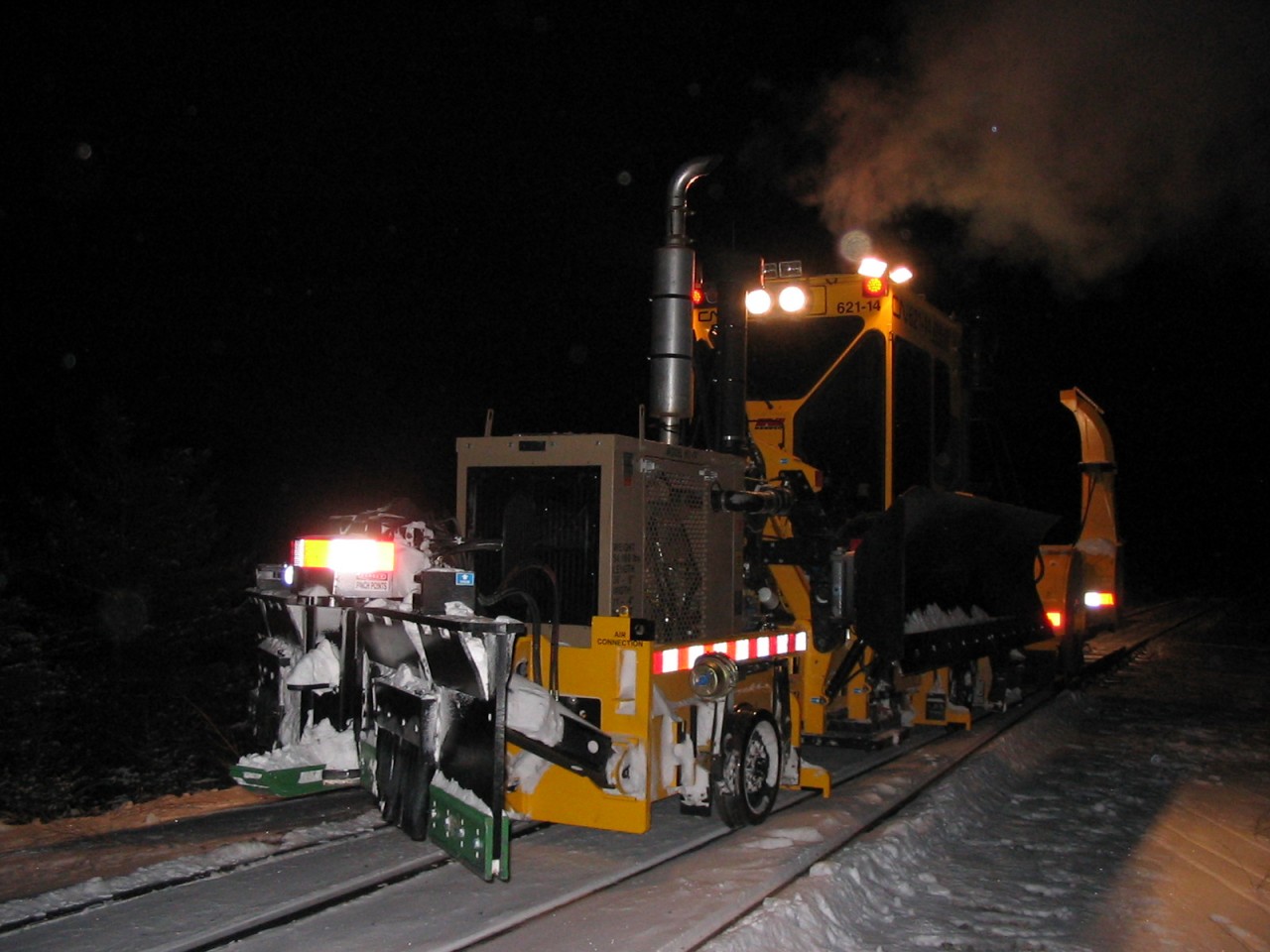 In contrast to Colin Arnot's August 30, 2016 photo of CN 621-14 working on a bright and warm summer day southeast of Edmonton (http://www.railpictures.ca/?attachment_id=26526), here is the same unit on her maiden voyage dressed in full winter gear, working hard to clear CN's Sangudo Sub. about 12 miles northwest of Whitecourt, Alberta on the night of January 12, 2005.  I took this photo at 20:49 hrs. while standing in -30C temperatures as evidenced by the exhaust smoke hanging in the air. The track beside and behind the machine have been plowed and winged clear and we are getting ready to sweep the turnout before heading back to Whitecourt for the night. While it is always an adventure putting new machines into service, I can honestly say that I don't miss those frigid days and nights with snow removal equipment.