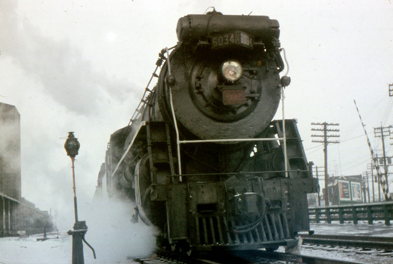 Tiny icicles have formed on the headlight of CN U1b 4-8-2 6034 stopped at West Toronto station. This Clayton Morgan photo is taken on a rather chilly February 15, 1958. My photo program removed a small spot in the upper left of the picture. I now realize it was the sun shining through ice crystals in a cloudy sky.