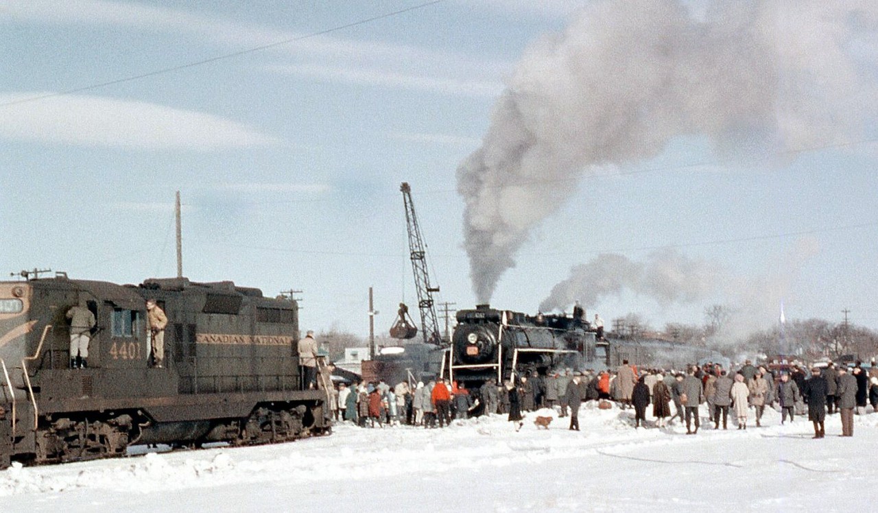 Canadian National Northern 6167, on a winter UCRS steam excursion from Toronto to Lindsay and back, pauses at Lindsay as a clamshell-equipped crane loads her tender with coal. This was a frequent occurrence on steam fantrips in the diesel era when there were no steam facilities around, or they had all been removed. Fantrip riders, railfans and spectators crowd around her, with some climbing on nearby CN GP9 4401 to have a look in her cab (but she recieves little attention compared to the star of the show, 6167).More 6167 excursion photos:Crew lubricating her running gear at Lindsay: http://www.railpictures.ca/?attachment_id=17715On a UCRS excursion near the Humber River in Etobicoke: http://www.railpictures.ca/?attachment_id=25751To Picton/Prince Edward County: http://www.railpictures.ca/?attachment_id=14252Final 6167 fantrip, with 6218: http://www.railpictures.ca/?attachment_id=14528