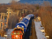 In the winter of 2014 CP 5926 & CP 4506 head west with a relatively short train of windmill tower sections about 45 minutes before sunset as they split the advance station sign for Valois.
