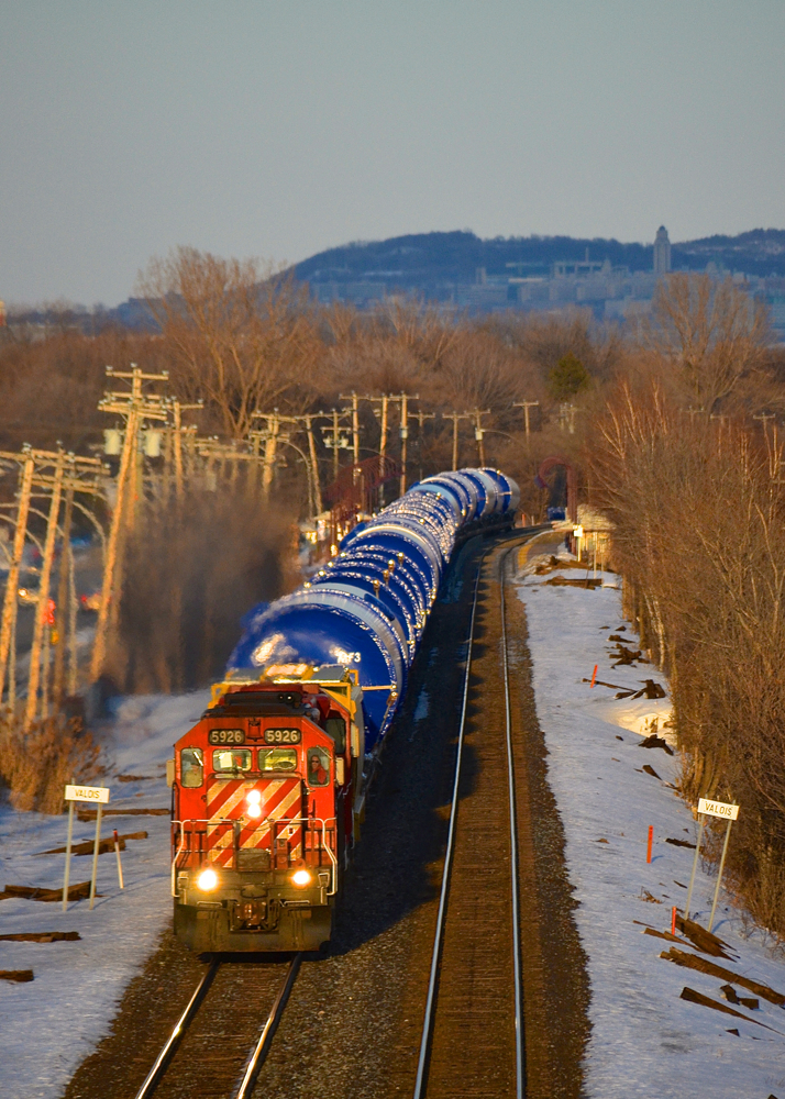 In the winter of 2014 CP 5926 & CP 4506 head west with a relatively short train of windmill tower sections about 45 minutes before sunset as they split the advance station sign for Valois.