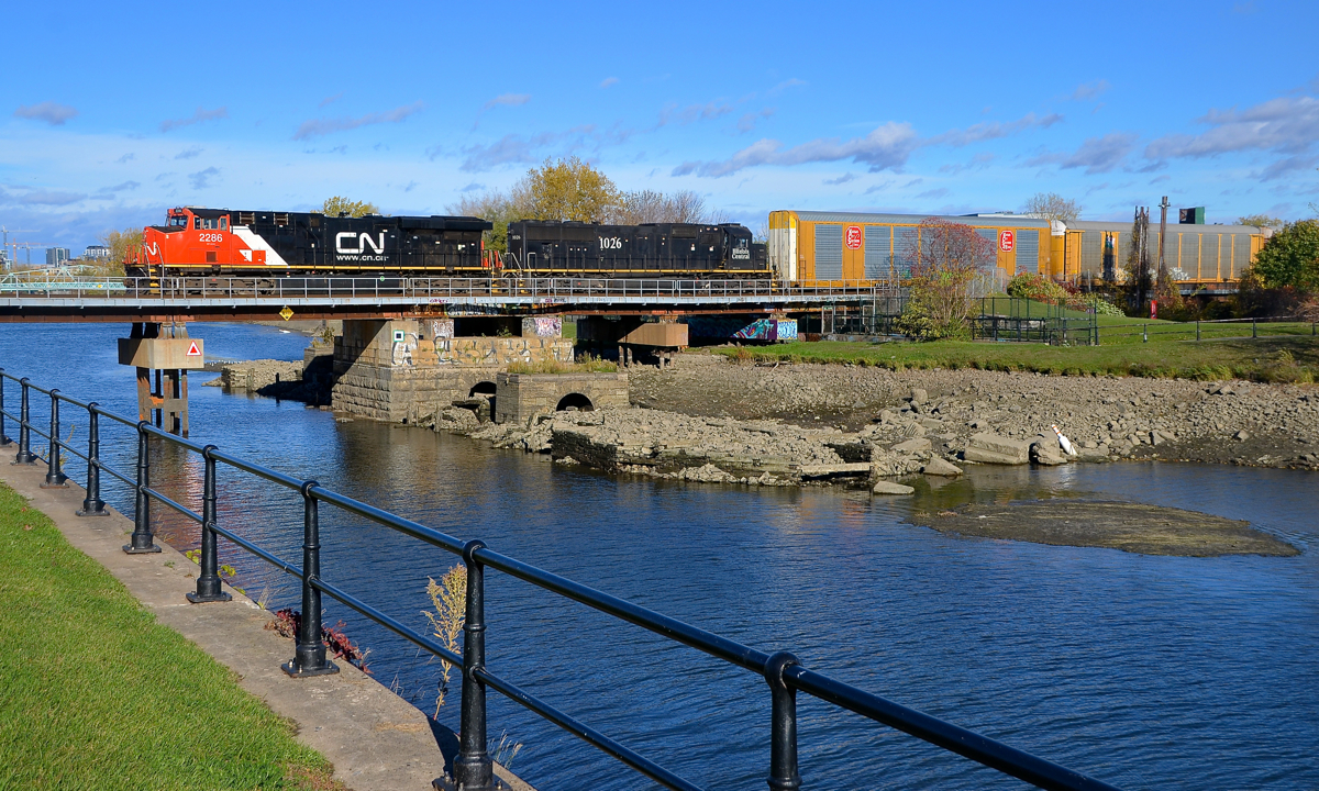 Remains of the old swing bridge. CN 2286 & IC 1026 lead a short (70 cars) CN 401 over the Lachine Canal on an afternoon where Montreal saw sun after many days of rain. The train is passing over the supports that held a swing bridge before the old bridge was replaced during the early 1990s. Every fall the canal is partially emptied, allowing the remains to be seen.