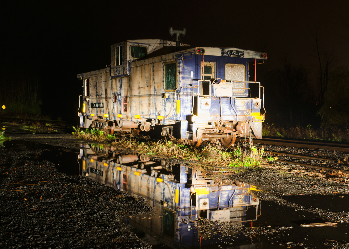 CN 79834 is seen reflected in the puddles after a rainy day in Vankleek Hill on CN's Vankleek Spur. This caboose was built by CN in their Pointe St-Charles shop in Montreal under the same number. CN sold it to the Ontario L'Orignal Railway (OLOR) in 1996, which was taken over by the Ottawa Central Railway. In 2008 CN took over the Ottawa Central and renumbered the caboose back to its CN number. It is used for backup moves on the L'Orignal Spur and is not in good shape.