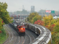 <b>A pair of trains in the rain.</b> As the rain falls, CN 527 is about preparing to back up and set off some cars at Turcot West, with CN's last SD75I (CN 5800) leading. At right grain train CN 874 is awaiting a new crew before heading east.