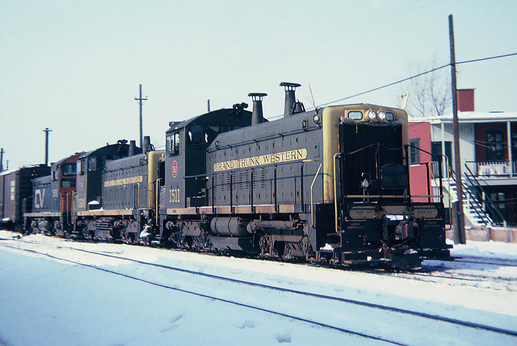Central Vermont train 444 returning to Italy yard at St.Albans, Vermont, leading the train three EMD SW1200s two Grand Trunk Western Numbers 1511 and 1510 with a Central Vermont No.1500   December 14, 1965.