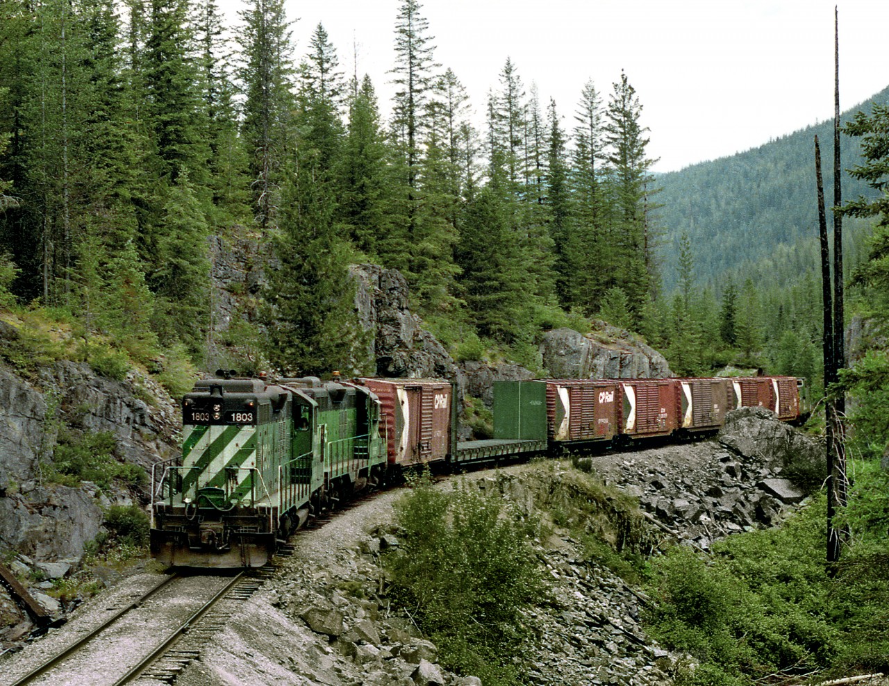 Southbound BN Nelson Local passes a rock bluff between Nelson and Ymir on its run to Kettle Falls WA, with a layover at Salmo BC. Great Northern Geeps ran long nose first