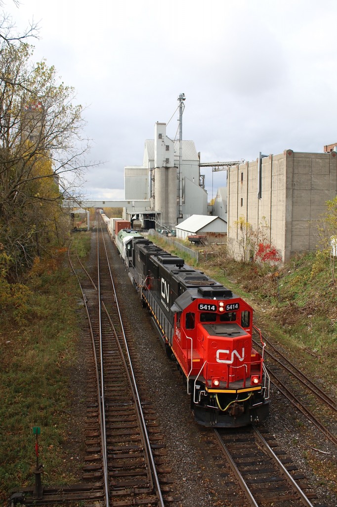 The sun is trying ing to fight its way through the clouds at Woodstock as train 148 rolls past the landmark Purina elevator. Today's consist has a recently repainted former Oakway SD60 along with an IC SD70 hauling brand new GO Transit MP40PH 664 to its new home in Toronto. Of note at this location is the former south service track for the elevator that has lost its frog for the switch. I believe the switch has since been fully removed. The north service track is still in service here.