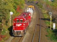 <b>Splitting the pre-CTC signals.</b> Until the summer of 2014 CP's Vaudreuil Sub between Dorval and Dorion was governed by OCS/ABS regulations and this pair of searchlight signals stood just east of a pedestrian overpass in Beaconsfield. Here in great light a pair of GP38-2's and a caboose bracket three tank cars as the Dorion Turn splits the signals. The signal at right is lit for an eastbound which will pass in a couple of minutes. The entire Vaudreuil Sub is now CTC and these signals are now gone. 