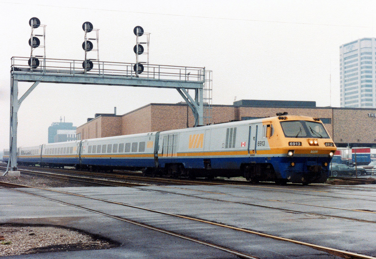 LRC locomotive Via 6913 is about to cross Colbourne St. as it leads four coaches out of London, ON and becomes the first train to pass the newly commissioned CTC signal 774 at McLeod on this cold, drizzly and overcast day in December of 1982.