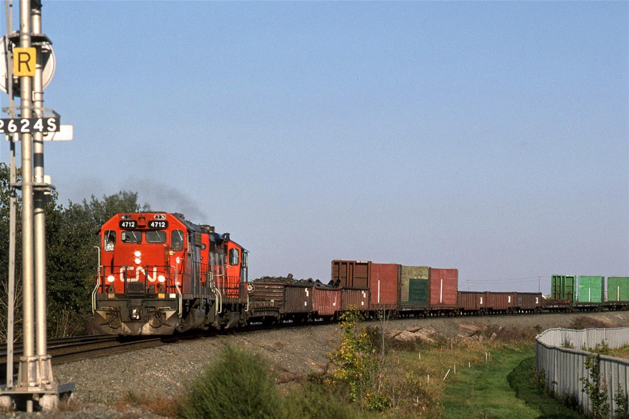 Now, the Camrose Turn returns to Edmonton with gondolas of scrap metal and bulk-head flats. At the time, there was a metal scrap yard and a facility that received logs on the north side of Camrose.