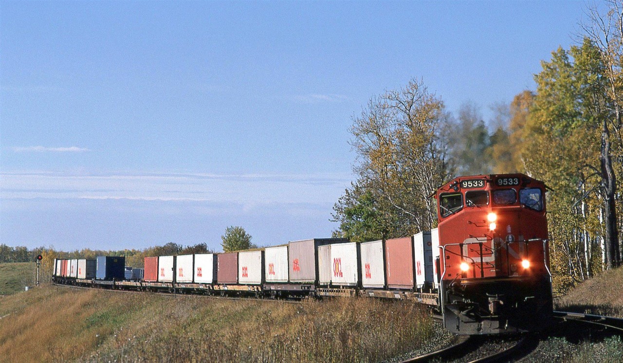 An eastbound COFC train rounds the curve above Mink Lake at Carvel. Out west, the trees don't become the multi-coloured wonders like down east - they go yellow and very shortly thereafter are blown off the limbs by the inevitable strong winds accompanying the cold fronts that come through.