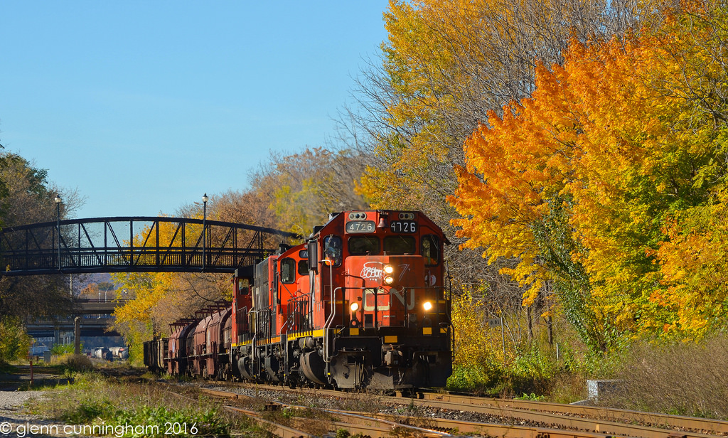 Tr 550 with 4726, 7068 and 4785 is on the move in the service track at Hamilton ON on their way to the north main of the Grimbsy Sub to set off cars at the CN Steel Transload facility at Parkdale Ave. Classic GM power with a splash of Fall colour.
