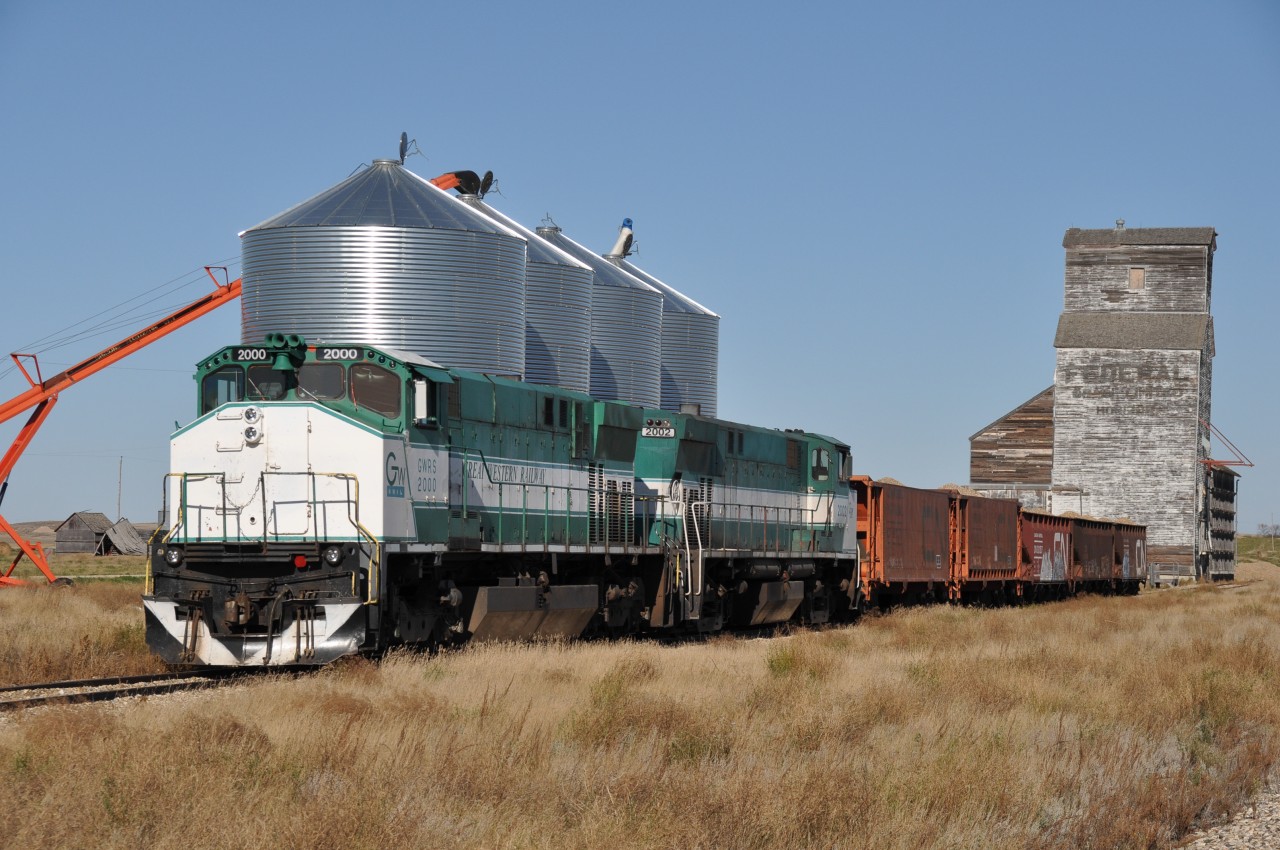 Driving east along Hwy 13 in southern Saskatchewan, I looked over to the south as thee were a couple of old grain elevators in the distance. And, somehow, from about 2 KM away I picked out what looked to be an engine, rather than the usual grain cars. Talk about luck!!! The hamlet of Horizon is something else. The two existing grain elevators are historically unusual, and the "town" is reduced to a church, perhaps closed, and a couple of houses by the look of it. Might be 10 people there, all told; for it lost its status as a community more than 40 years ago. A Saskatchewan ghost town!! The road in is rough gravel, and the main introduction to the place is a decrepit old shack at the first intersection, surrounded by weeds and neglect. When checking google maps I found it rather hard to believe the drive up to the elevators off the "main road" actually qualified as streets and were given names. And it was very surprising to see a ballast train of the Great Western Rwy to be parked on the siding here; as this is actually trackage of the Red Coat Road & Rail. This is operated by the adjacent Great Western, but I noted a long line of stored cars had severed the two roads, so expected to find nothing but the Southern Prairie Rwy at nearby Ogema, which is a tourist operation and I thought it was now the sole reason for the Red Coats' existence. But the ballast trains' presence suggests a brighter future ahead. GWRS 2000 and 2002 with 5 cars of ballast await the start of the work week, nestled between two of the most unusual elevators I have seen in a while. (The other is to my back) This pair of M420s I suggest have very few years of service left. They were built in 1973 & 1974.