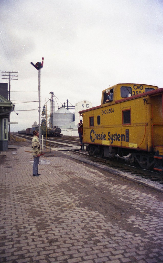 Forty years ago yesterday as of this posting there were still mainline freights passing thru Blenheim, Ontario. I know from my notes that this long freight had C&0 3044, 3568, 3046, 5753 and 5708 up front for power eastbound, but this is before the days I had a programmable scanner. Available to me only was the old under-dash Patrolman, which involved individual crystals at $5.95 a pop from some outfit in Oakville, and I did not have the money back then to buy crystals for areas outside of the Hamilton/Burlington area. So, I did not get transmissions nor a train number. C&0 station agent talks to on-train employees as they slow down to set off some cars in this old time rather up-front and personal scene. The building in the background is K.C. Fertilizers Ltd. The image, scanned from a negative of some substandard film I bought back then, was shot using a Miranda Sensorex RE. A junker of a 35MM camera in my case...............