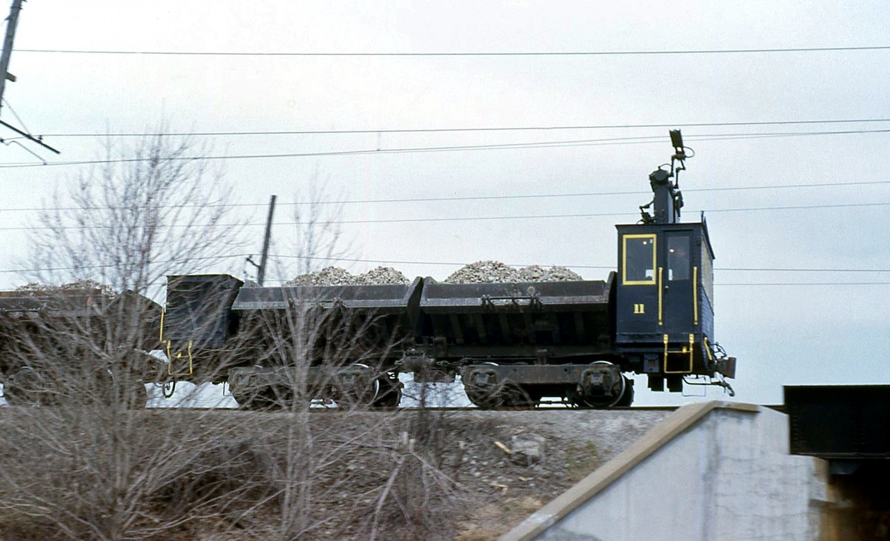 Canada Crushed Stone electric dump motor 11 is pictured hauling loads of excavated material along the line from their Greensville quarry in April 1963. One of four units built by Canadian Car and Foundry in 1933 (units 8-11), 11 and her sisters were used for hauling excavated material from the upper quarry areas to the dumper on the hill at CCS's plant in Dundas (now the site of "Dundas Peak"). They also hauled dumper cars carrying material that were coupled behind. Electric operations at CCS ended in 1975.

A view of part of the plant by CN's Dundas Sub, as captured by Arnold Mooney: http://www.railpictures.ca/?attachment_id=14793