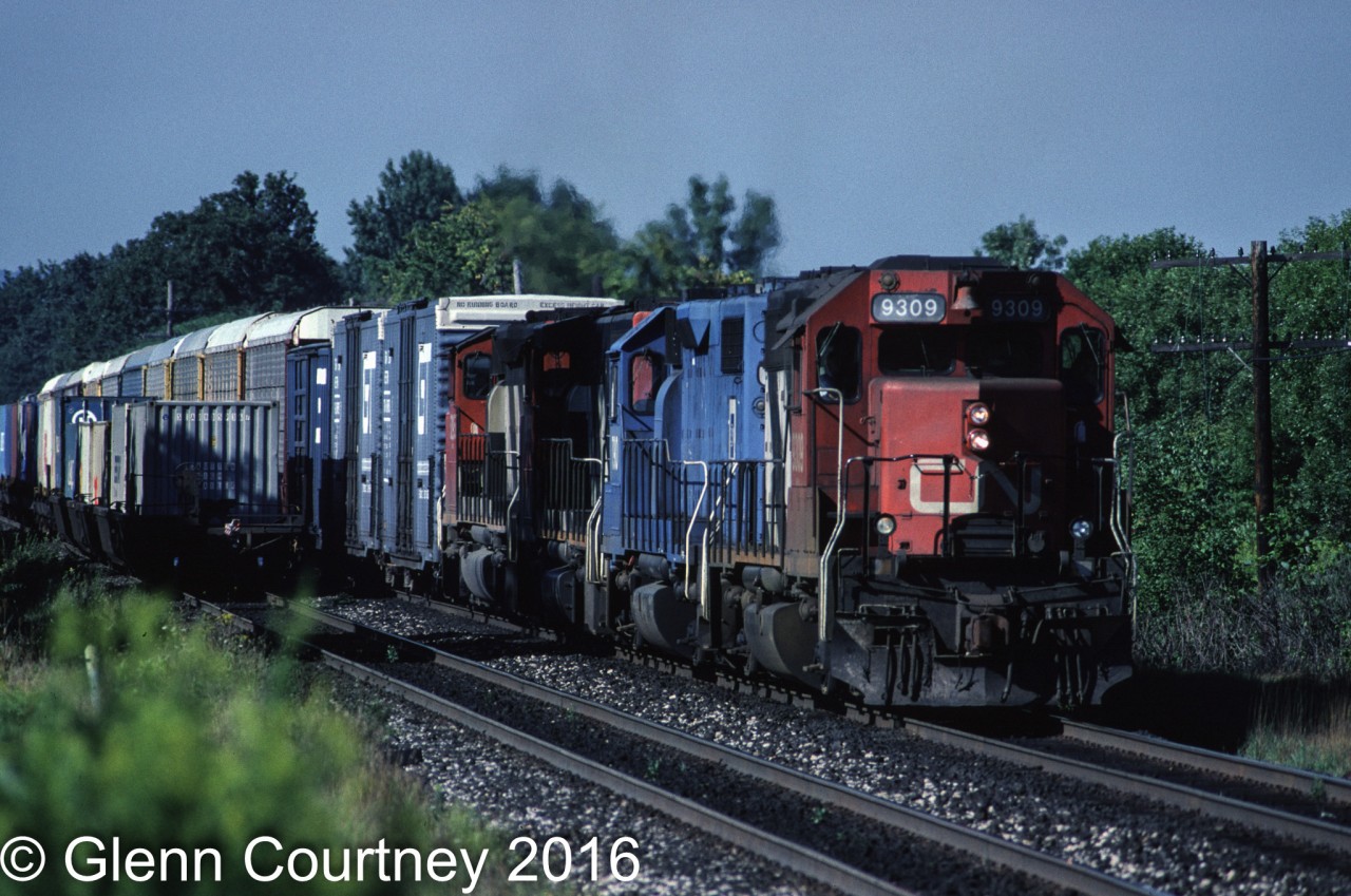 CN GP40 9309 has been sprung from captive service running through the tunnel between Sarnia, Ontario and Port Huron, Michigan and is leading train #272. The train is approaching Aldershot near the site of current day Snake. The second unit is a former Conrail GP38-2 that went into EMD's lease fleet when their lease expired. CN had some on lease for awhile. 

This was one of those days when I was the windshield and not the bug as the westbound got by just in time for me to get the shot.
