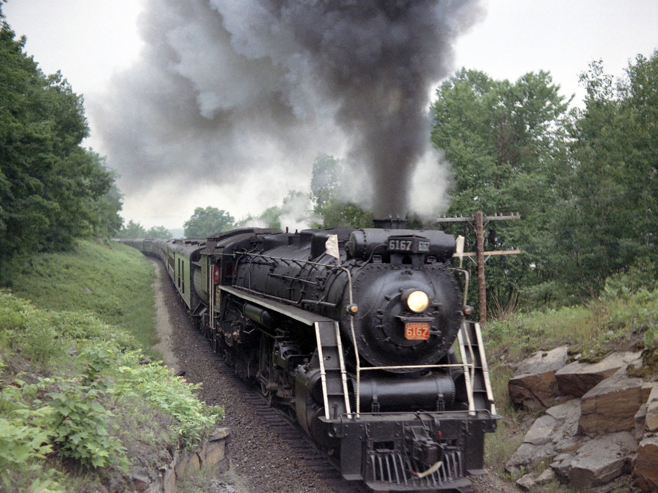 Flying white flags and showing off a good head of steam, CN U2e Northern 6167 snakes through the rocks of Muskoka near Bracebridge, operating on a fantrip in 1963.

(Note, geotagged location not exact).