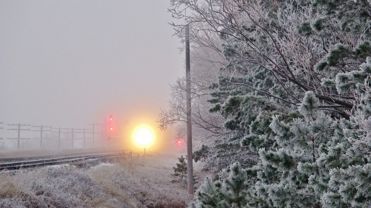 Piercing through the fog, a CN SD70M-2 blasts through the frosty prairies with a fast stack train in tow near Dugald, MB on a cool November morning.